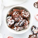 Overhead view of a red and white striped bowl of gluten-free chocolate peppermint pretzels.