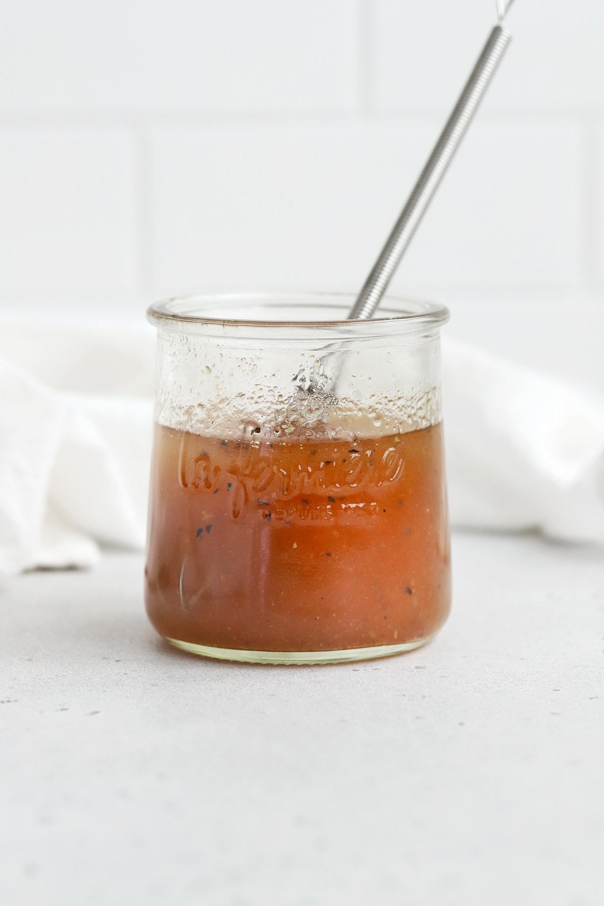 Front view of a jar of red wine vinegar dressing on a white background