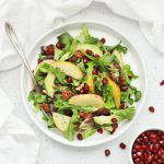 Overhead view of pear pomegranate salad on a white background