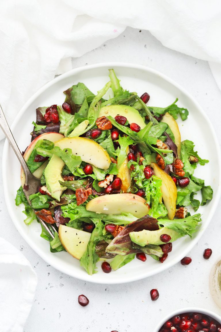 Overhead view of pear pomegranate salad on a white background