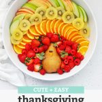 Overhead view of a Thanksgiving turkey fruit plate with text overlay that reads "Cute + Easy Thanksgiving Turkey Fruit Plate: Simple + Fun + Adorable!"