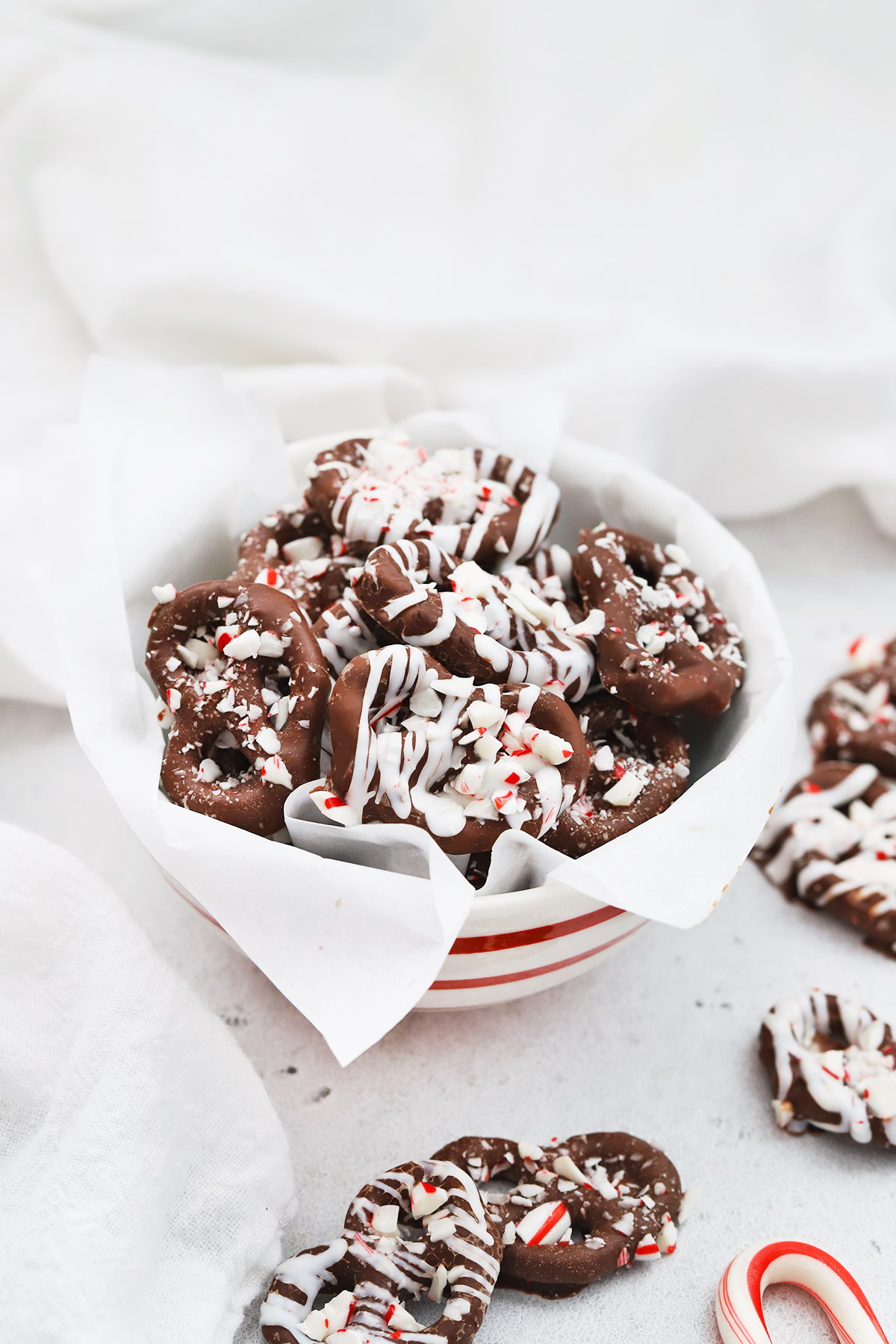 Front view of a red and white striped bowl of gluten-free chocolate peppermint pretzels.