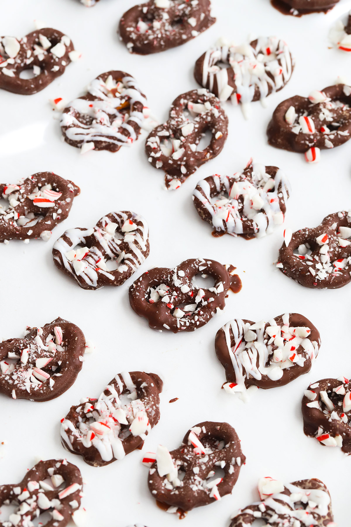 Overhead view of gluten free chocolate peppermint pretzels sprinkled with crushed candy canes on a white background.