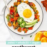 Overhead view of a plate of Southwest Sweet Potato Hash topped with an egg with plates of bacon and orange wedges on the side with text overlay of "paleo + Whole30 + vegan Southwest Sweet Potato Hash"