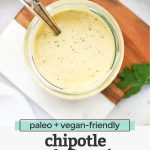 Overhead view of a jar of chipotle ranch dressing with a spoon in it with text overlay that reads "paleo + vegan-friendly chipotle ranch dressing: for salads + tacos + burgers + wraps + more!"