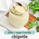 Front view of a jar of chipotle ranch dressing with a spoon in it with text overlay that reads "paleo + vegan-friendly chipotle ranch dressing: for salads + tacos + burgers + wraps + more!"