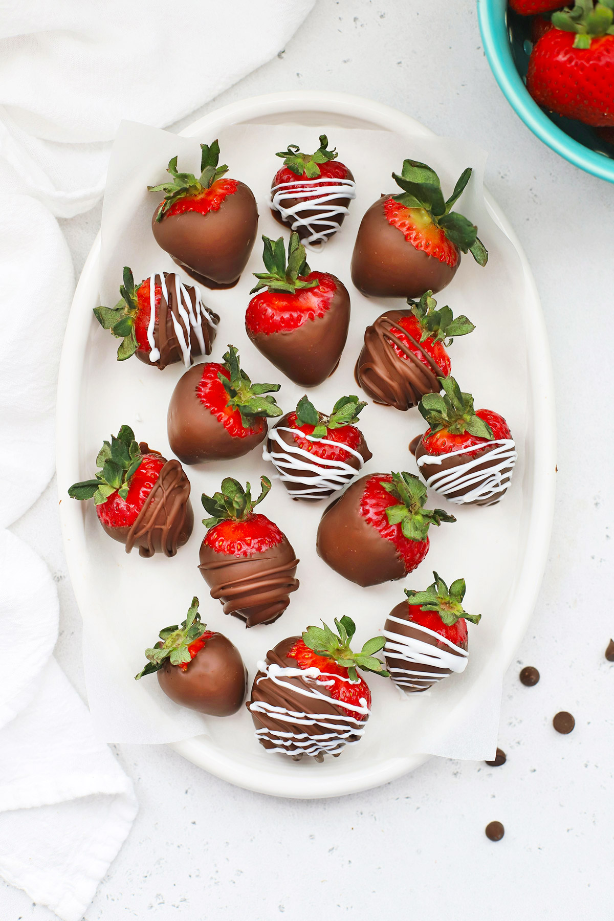 Overhead view of vegan chocolate-covered strawberries on a white oval plate