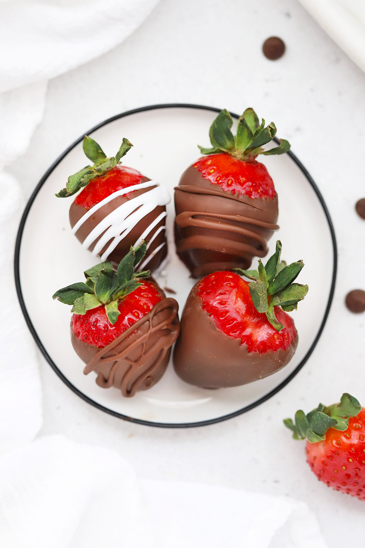 Overhead view of dairy-free chocolate covered strawberries on a white plate.