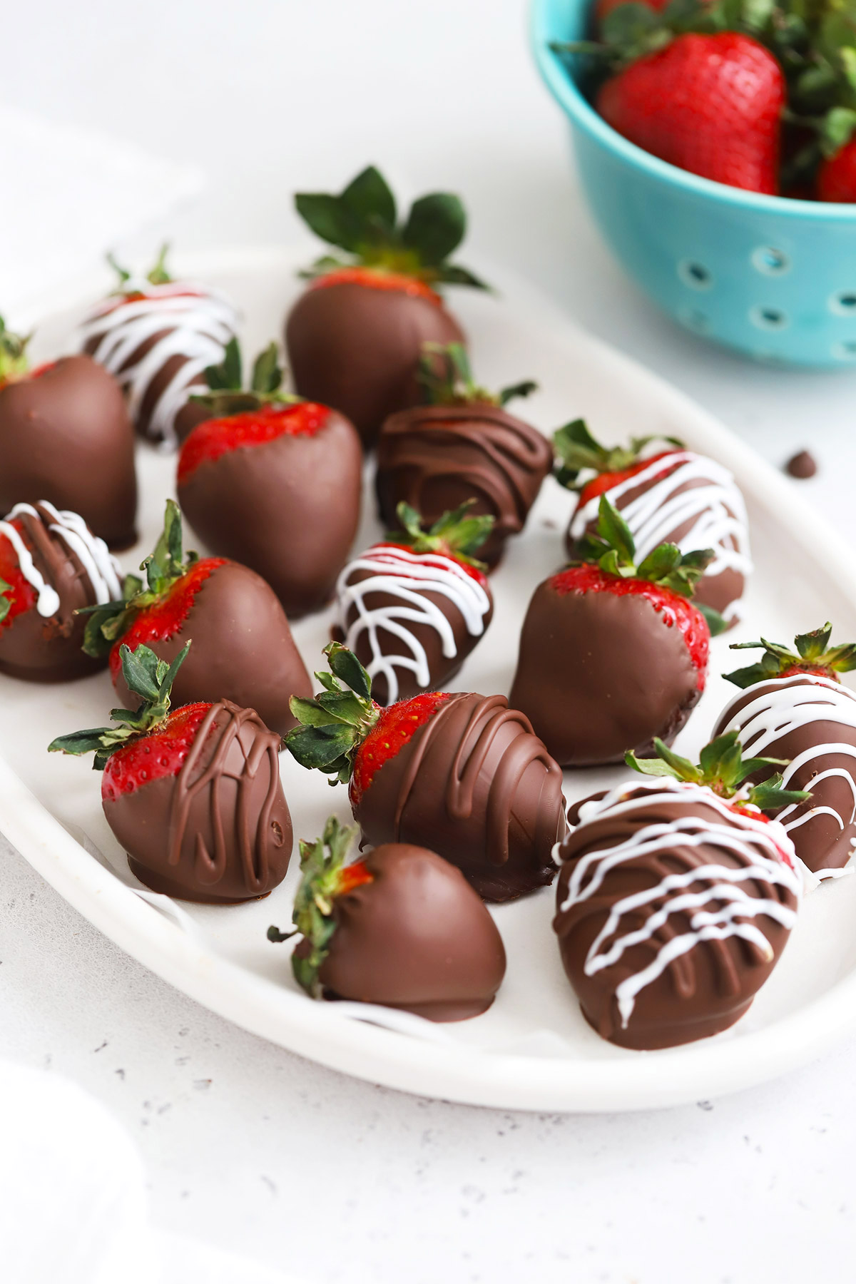 Front view of vegan chocolate-covered strawberries on a white oval plate
