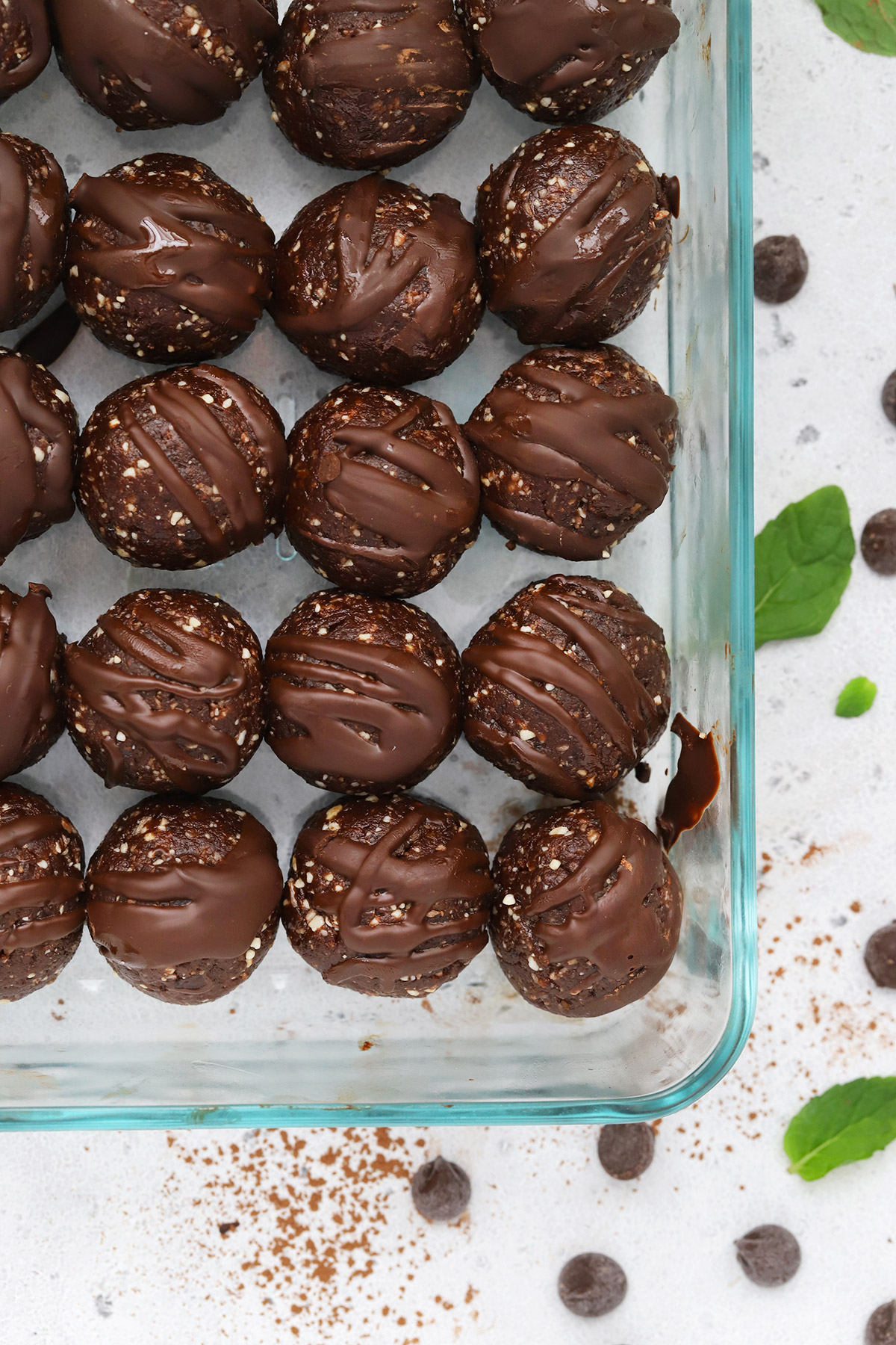 Close up overhead view of a meal prep container with mint chocolate energy bites drizzled with chocolate. 