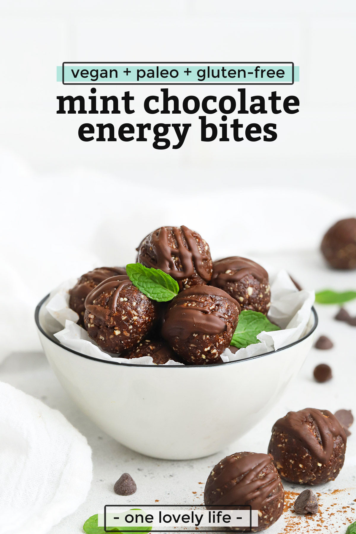 Front view of a bowl of mint chocolate energy bites with a few mint leaves. Text overlay reads "vegan + paleo + gluten-free Mint Chocolate Energy Bites"