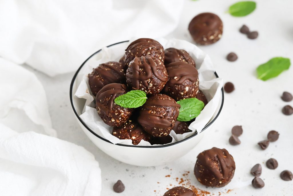 Front view of a bowl of mint chocolate energy bites with a few mint leaves.