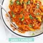 Overhead view of Paleo Slow Cooker Butter Chicken with rice. Small bowls of lime wedges off to the side with text overlay that reads "paleo + whole30 Slow Cooker Butter Chicken"