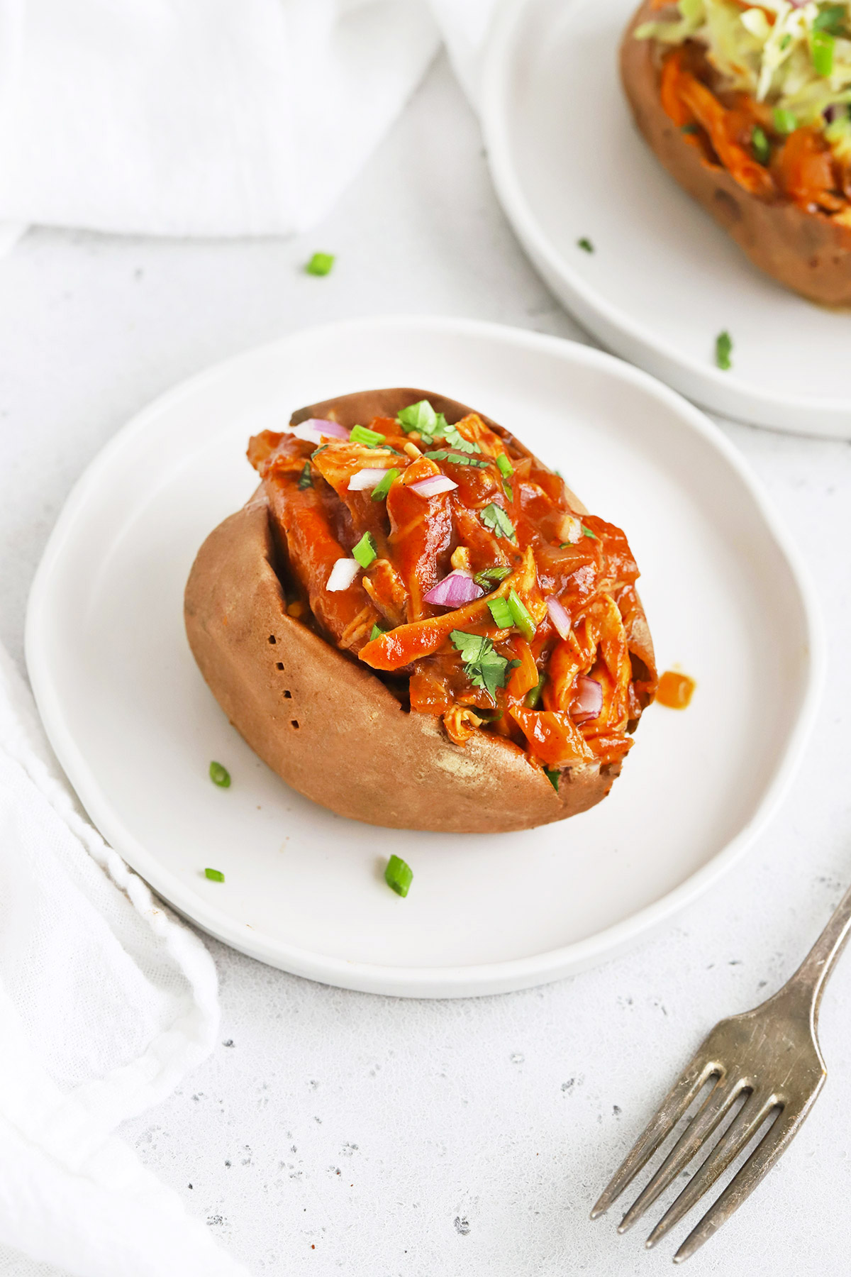 Front view of a BBQ Chicken Stuffed Baked Sweet Potato on a white plate