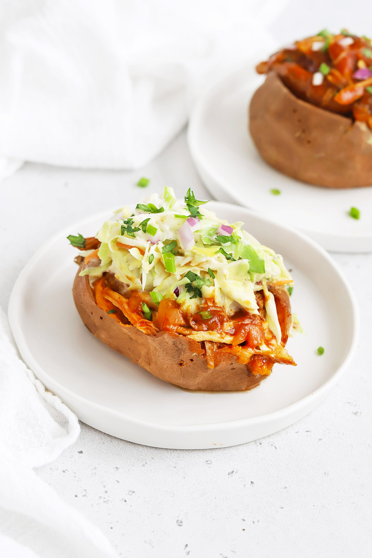 Front view of a BBQ Chicken Stuffed Sweet Potato Topped with Coleslaw on a White Background