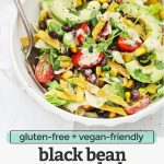 Front view of a white bowl of vegetarian black bean taco salad with crispy torilla strips and chipotle ranch dressing with text overlay that reads "gluten-free + vegan-friendly black bean taco salad with chipotle ranch dressing"