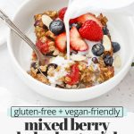 Front view of a slice of mixed berry baked oatmeal topped with fresh berries and sliced almonds with almond milk being poured on top with text overlay that reads "gluten-free + vegan-friendly mixed berry baked oatmeal: easy + cozy + berrylicious"