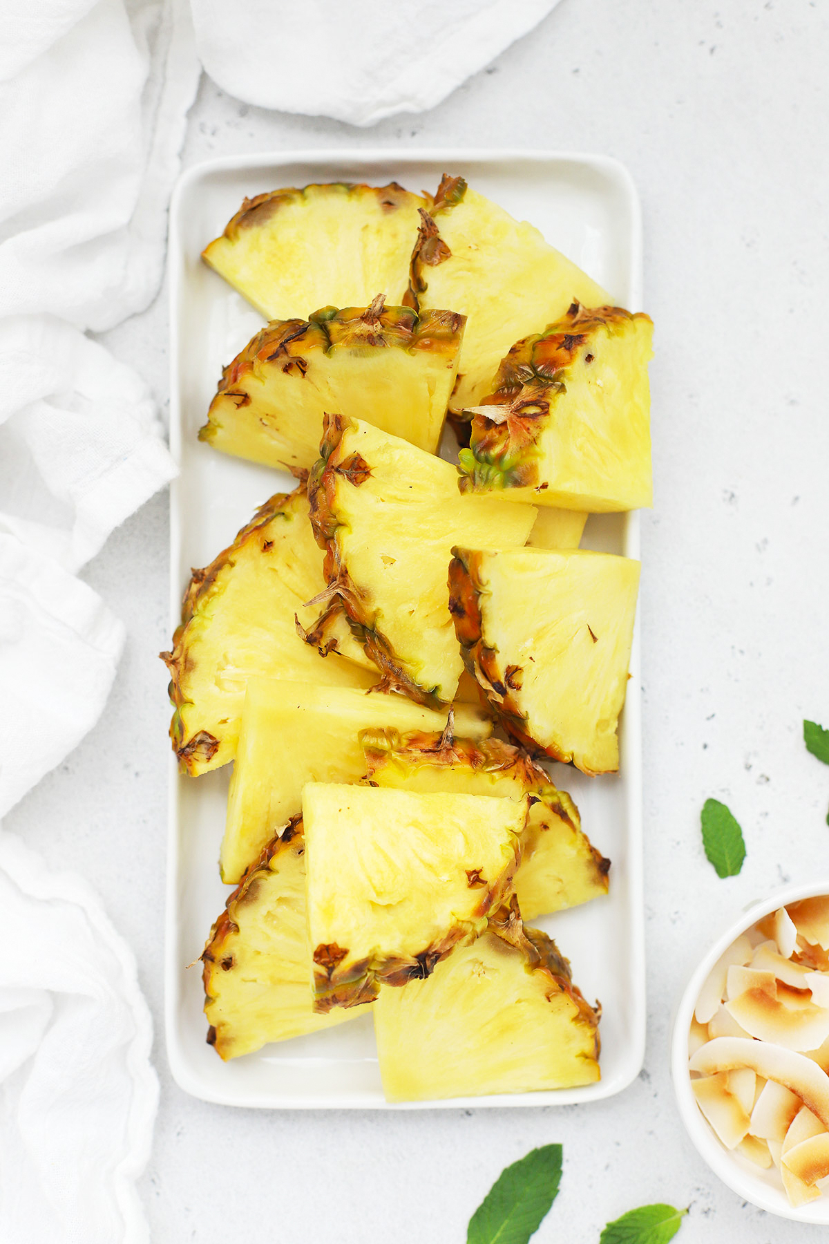 Overhead view of sliced wedges of fresh pineapple on a white platter