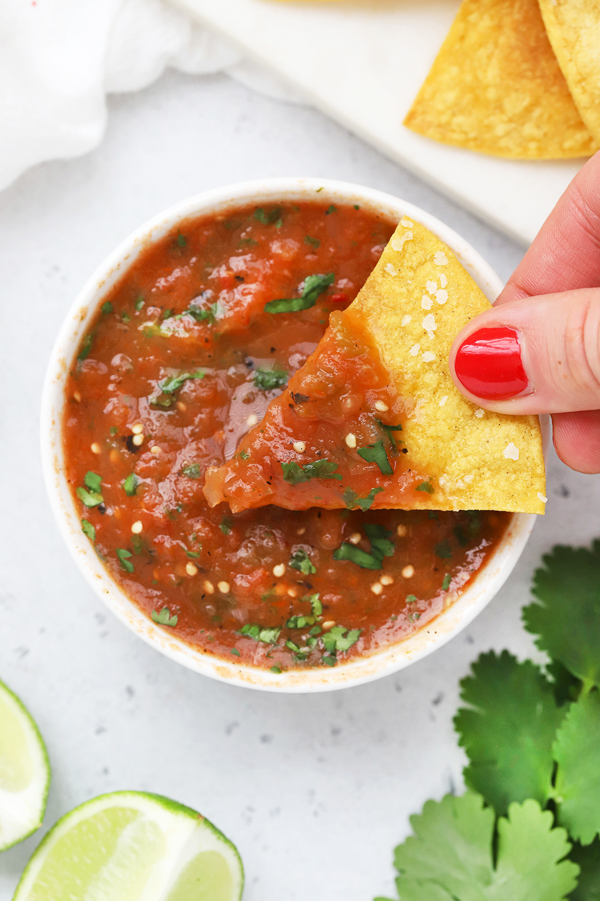 Close up Overhead view of a bowl of chipotle salsa on a white background with tortilla chips