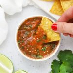 Overhead view of a bowl of chipotle salsa on a white background with tortilla chips