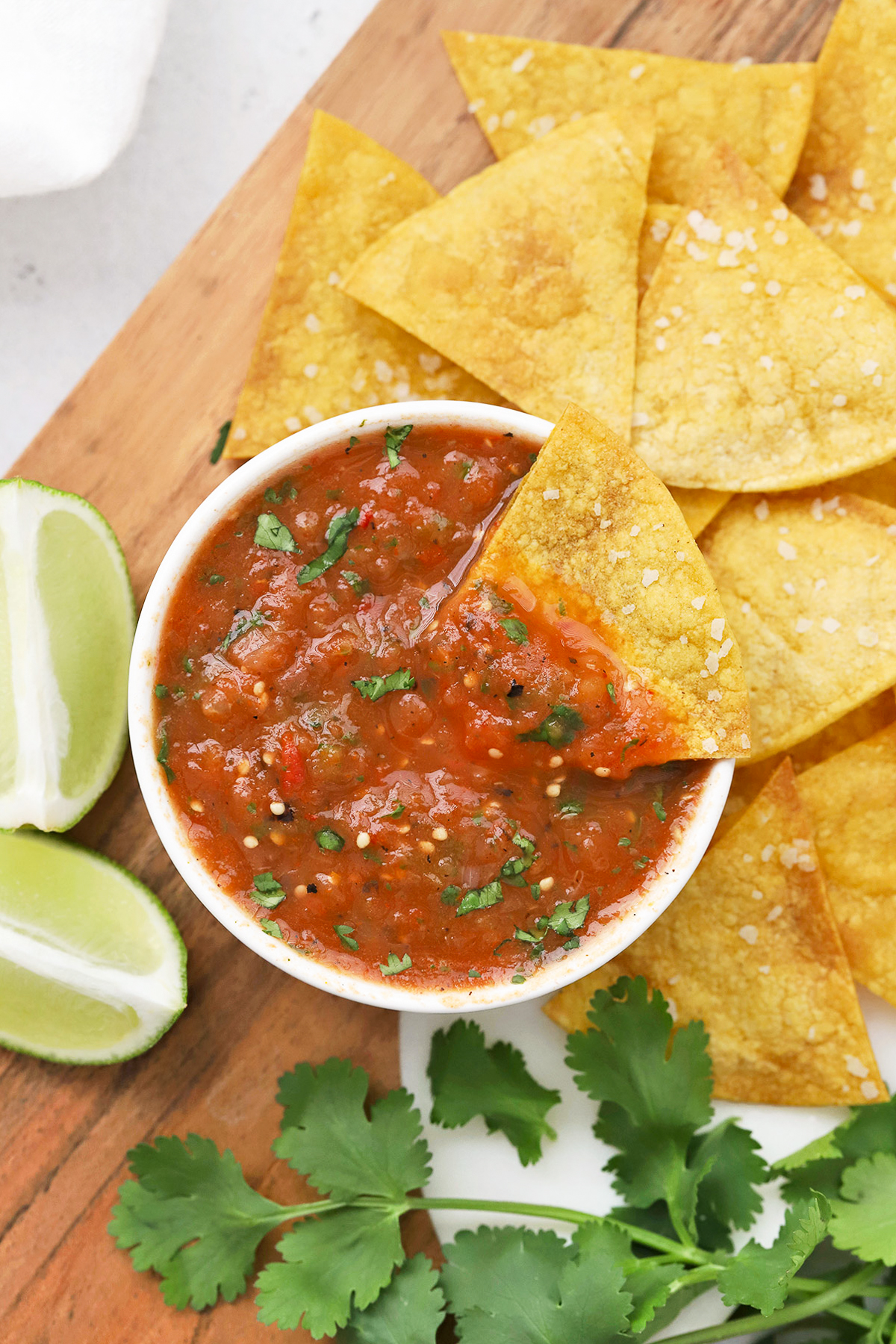 Overhead view of a bowl of chipotle salsa on a wooden board with tortilla chips