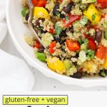 Front view of a bowl of Confetti Quinoa Salad in a white bowl on a white background with text overlay that reads "gluten-free + vegan-friendly confetti quinoa salad: fresh + light + easy"