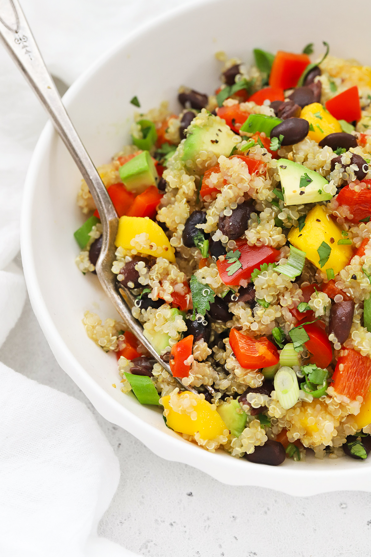 Close up Front view of a bowl of Confetti Quinoa Salad in a white bowl on a white background