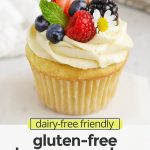 Front view of a gluten-free lemon cupcake with lemon frosting, fresh berries, and edible flowers on a white background with text overlay that reads "dairy-free friendly gluten-free lemon cupcakes: light + fluffy + irresistible!"