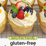 Close up Front view of gluten-free lemon cupcakes with lemon frosting, fresh berries, and edible flowers on a white background with text overlay that reads "dairy-free friendly gluten-free lemon cupcakes: light + fluffy + irresistible!"