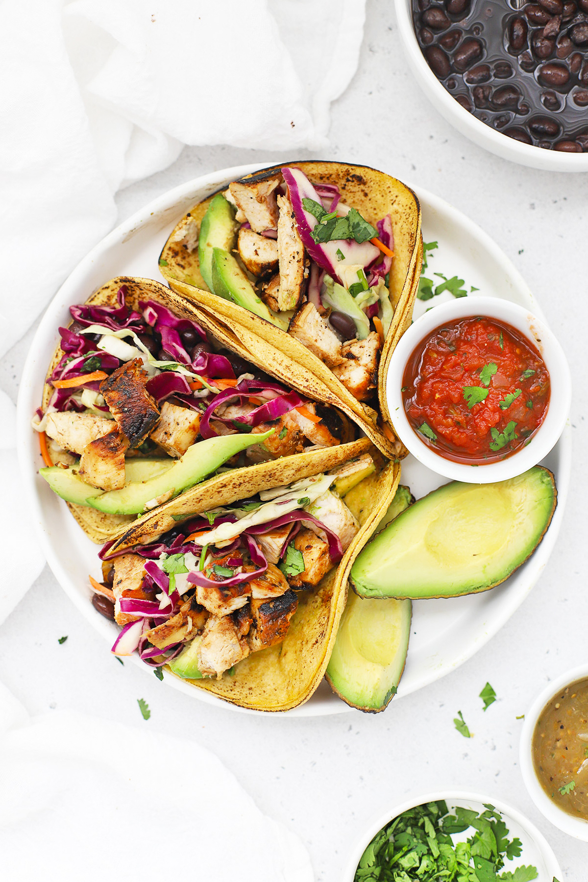 close up Overhead view of three honey lime chicken tacos with slaw on a white plate
