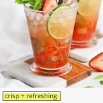 Front view of a non-alcoholic strawberry mint julep mocktail in a glass julep cup with text overlay that reads "crisp + refreshing virgin strawberry mint juleps"
