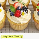 Close up Front view of gluten-free lemon cupcakes with lemon frosting, fresh berries, and edible flowers on a white background with text overlay that reads "dairy-free friendly gluten-free lemon cupcakes"