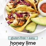 Front view of three honey lime chicken tacos with slaw on a white plate with text overlay that reads "gluten-free + easy honey lime chicken tacos: fresh + flavorful + fun"