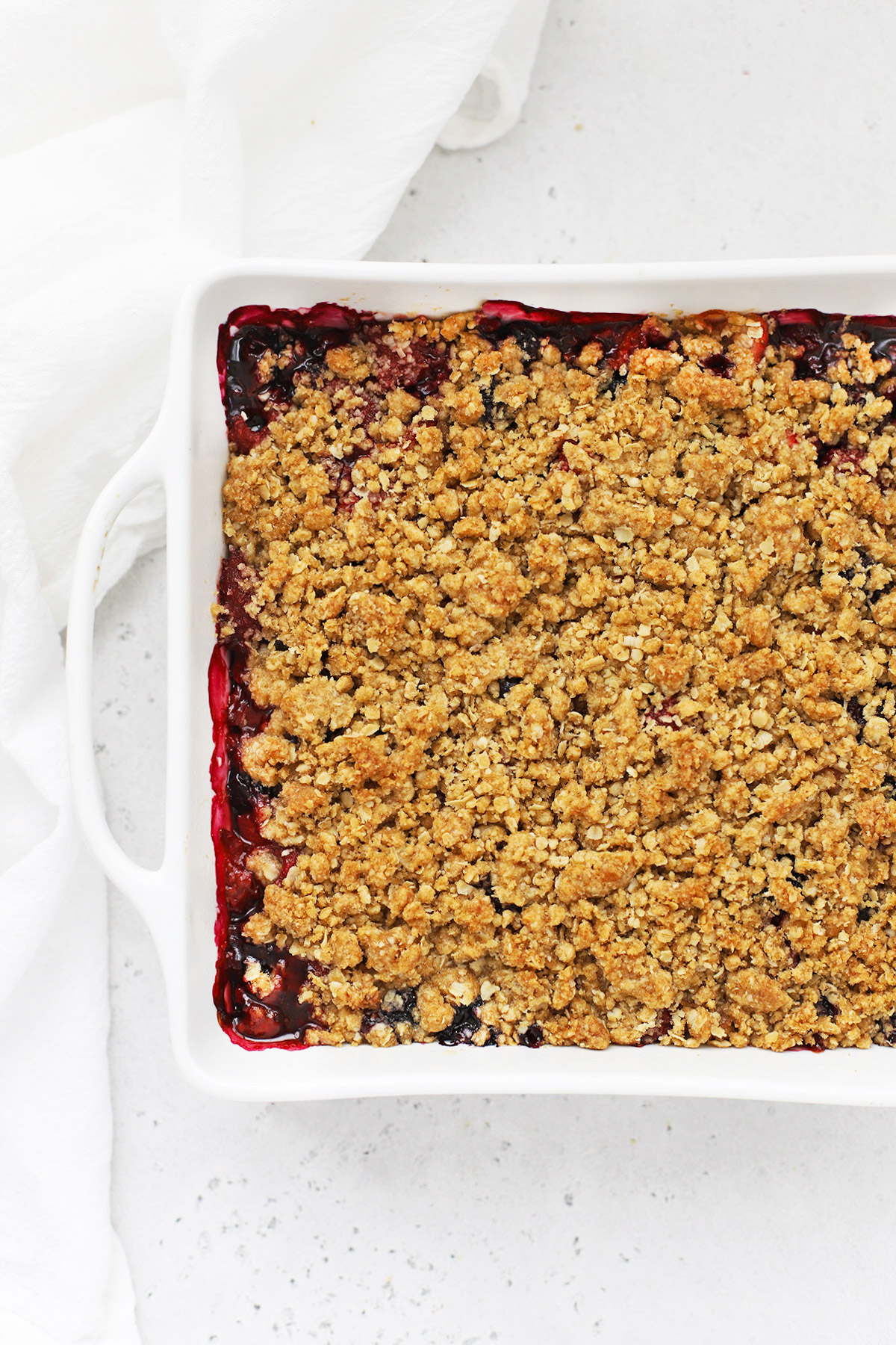 Overhead view of a baking dish of gluten-free berry crisp on a white background