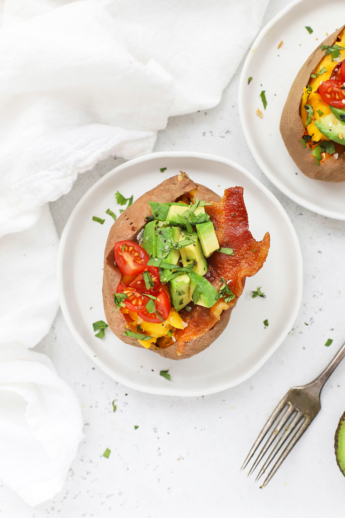 Overhead view of a California Breakfast Sweet Potato topped with bacon, eggs, avocado, and tomatoes.
