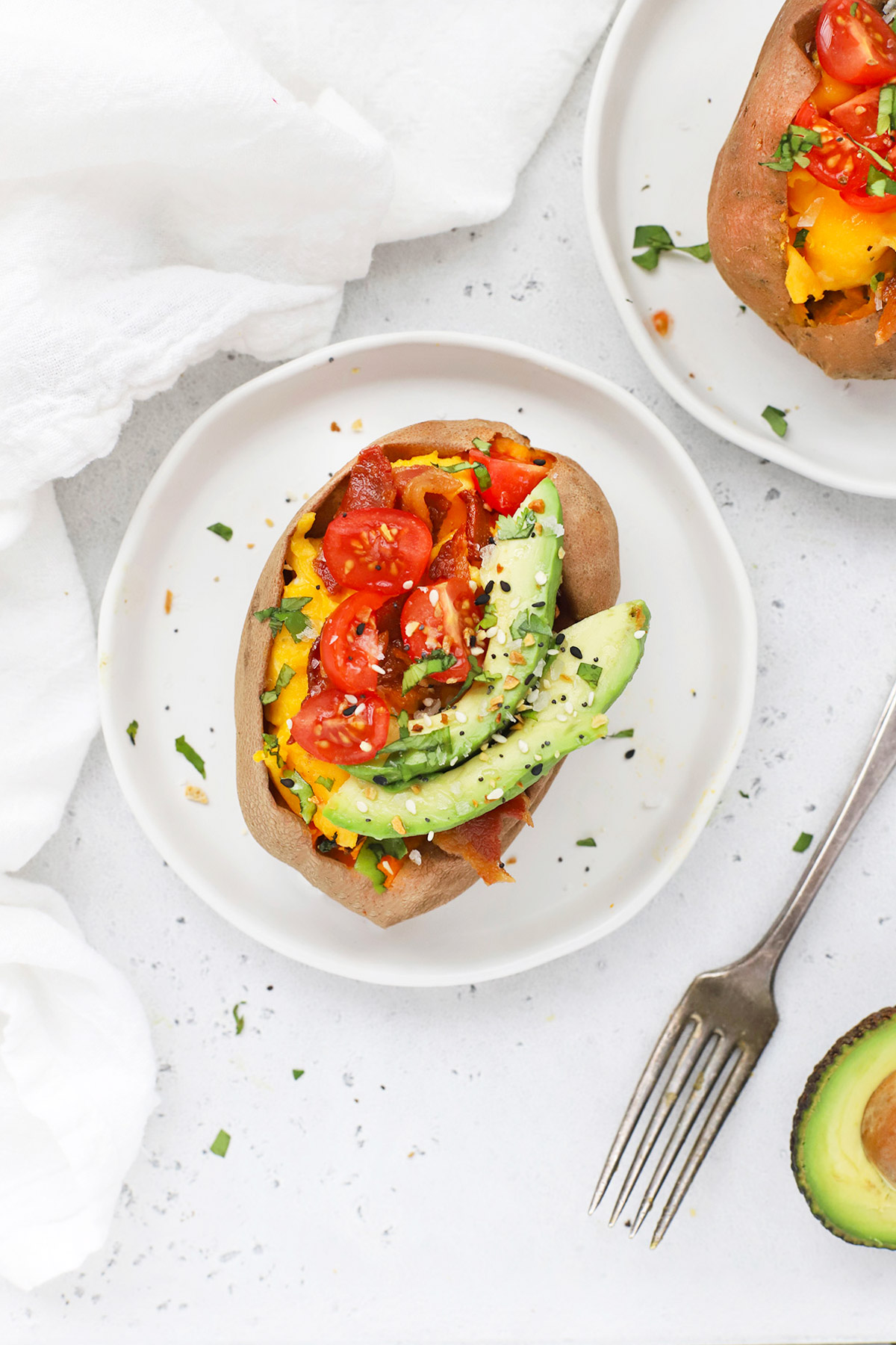 Overhead view of a California Breakfast Sweet Potato topped with bacon, eggs, avocado, tomatoes, and everything seasoning.