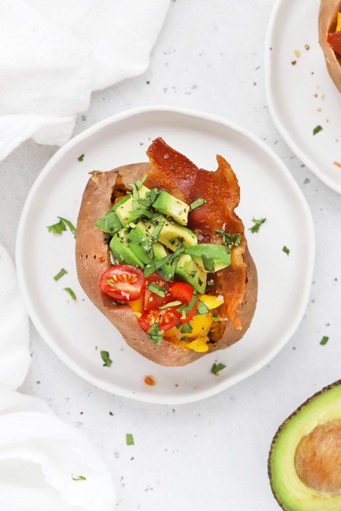 Close up Overhead view of a California Breakfast Sweet Potato topped with bacon, eggs, avocado, and tomatoes.