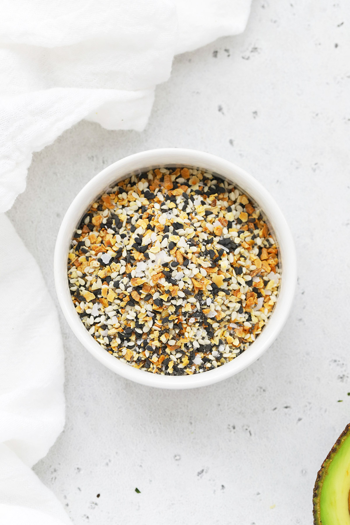 Overhead view of a bowl of everything bagel seasoning on a white background