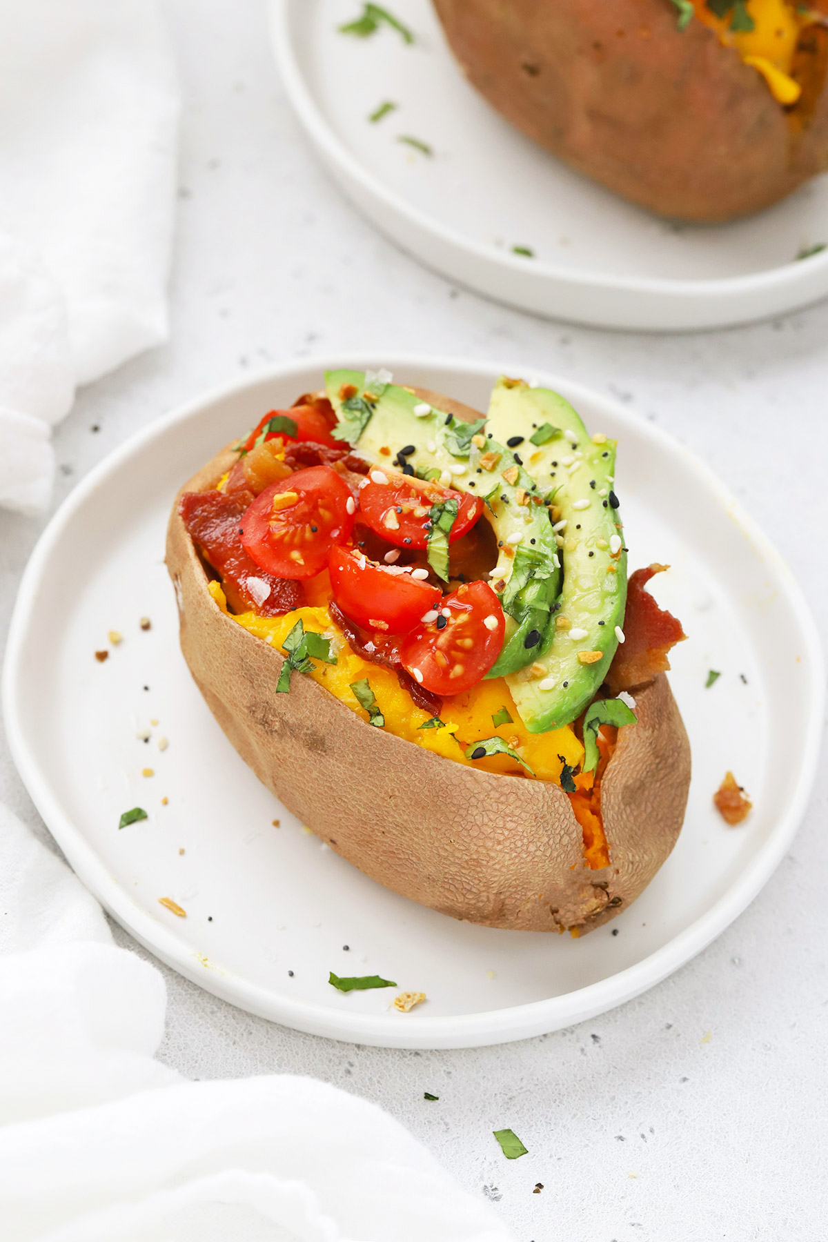 Front view of a California Breakfast Sweet Potato topped with bacon, eggs, avocado, tomatoes, and everything seasoning.