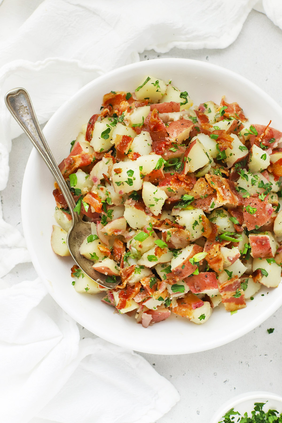 Overhead view of a white bowl of German Potato Salad with Bacon Dressing