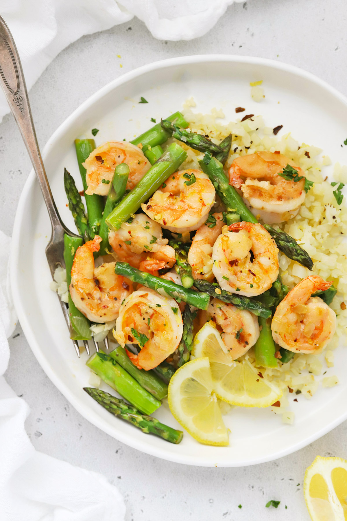 Close up overhead view of a plate of lemon shrimp and asparagus with cauliflower rice