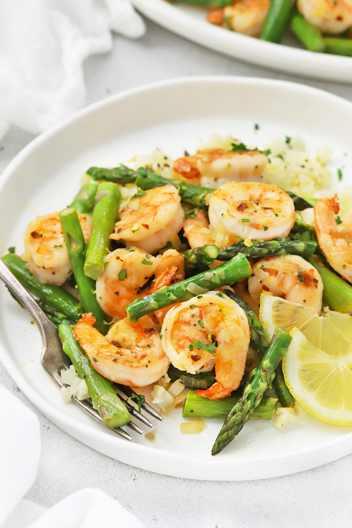 Front view of a plate of lemon shrimp and asparagus with cauliflower rice