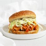 Close up front view of a slow cooker BBQ chicken sandwich on a white background