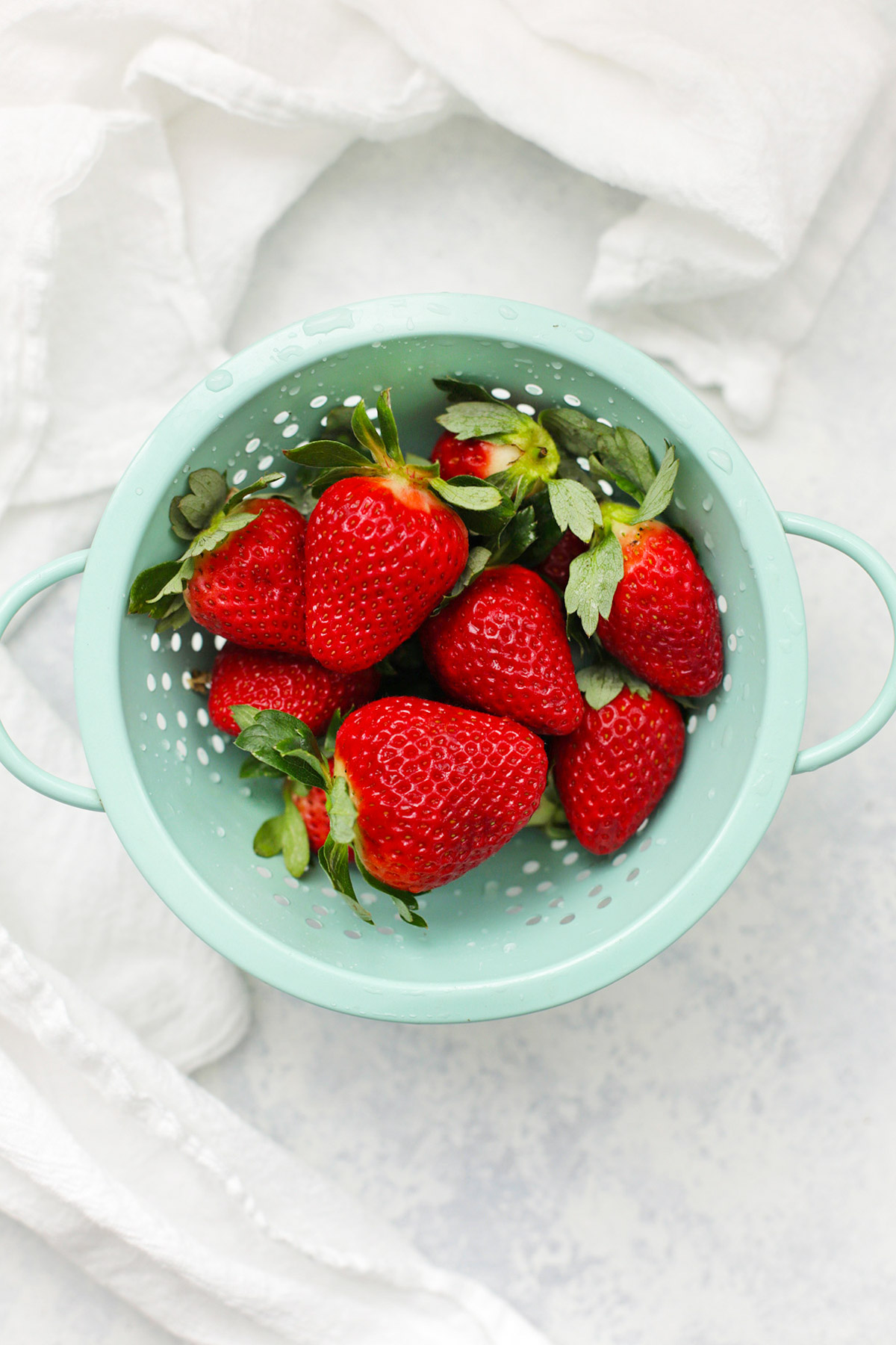 overhead view of a mint colander full of freshly washed strawberries