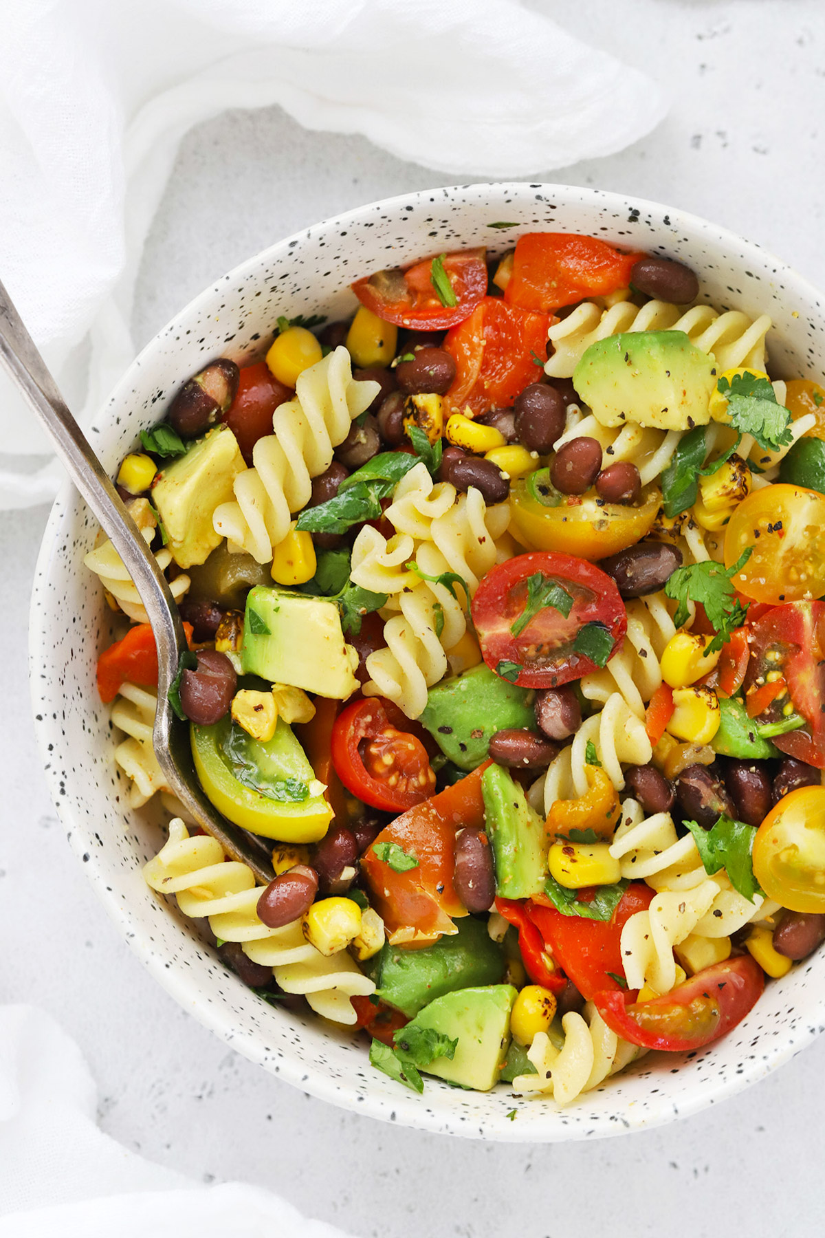 Close up Overhead view of a speckled bowl of healthy taco pasta salad on a white background
