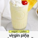 Front view of a virgin pina colada with whipped cream and a cherry on a white background with text overlay that reads "paleo & vegan virgin pina colada mocktails: quick + creamy + refreshing"