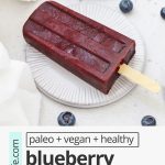 Front view of healthy blueberry pomegranate popsicles on coasters with text overlay that reads "paleo + vegan + healthy blueberry pomegranate popsicles: fresh + easy + delicious!"