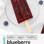 Overhead view of healthy blueberry pomegranate popsicles on coasters with fresh blueberries scattered around with text overlay that reads "paleo + vegan + healthy blueberry pomegranate popsicles: fresh + easy + delicious!"