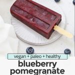 Front view of healthy blueberry pomegranate popsicles on coasters with text overlay that reads "paleo + vegan + healthy blueberry pomegranate popsicles: refreshing + simple + delicious!"