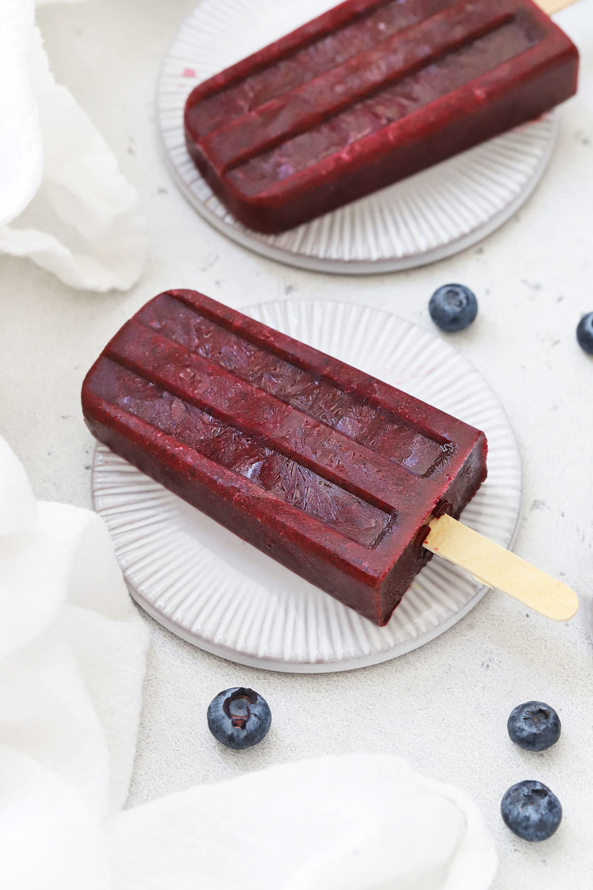 Front view of healthy blueberry pomegranate popsicles on coasters